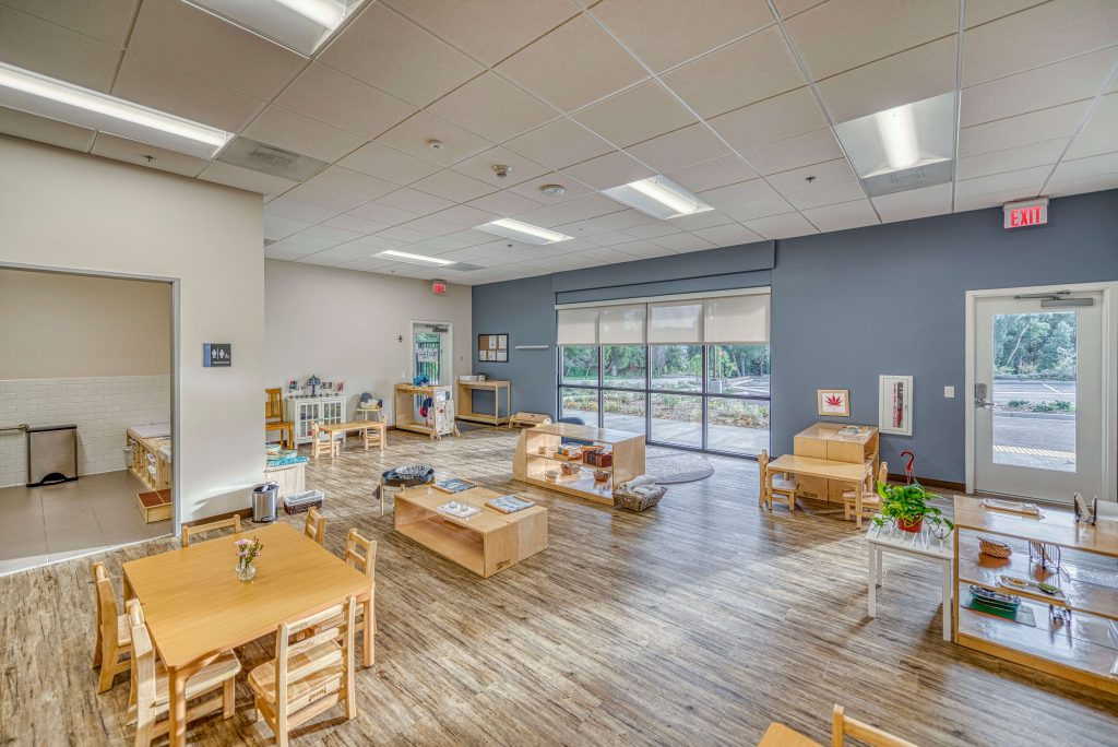 Montessori toddler classroom with natural wood furniture, open shelves, and large windows providing natural light at Guidepost Montessori.