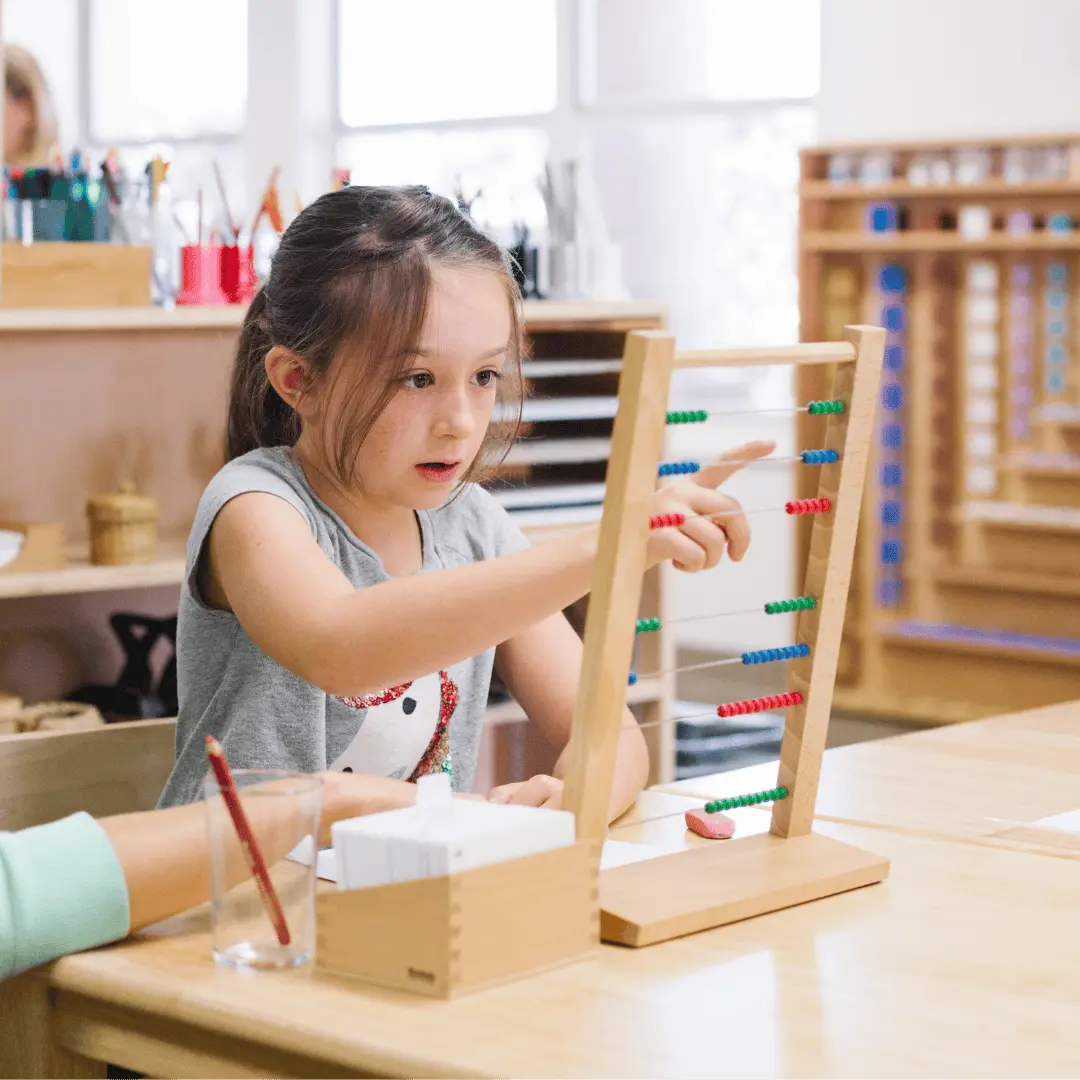 Montessori student counts colored beads on a math frame at Guidepost Montessori.