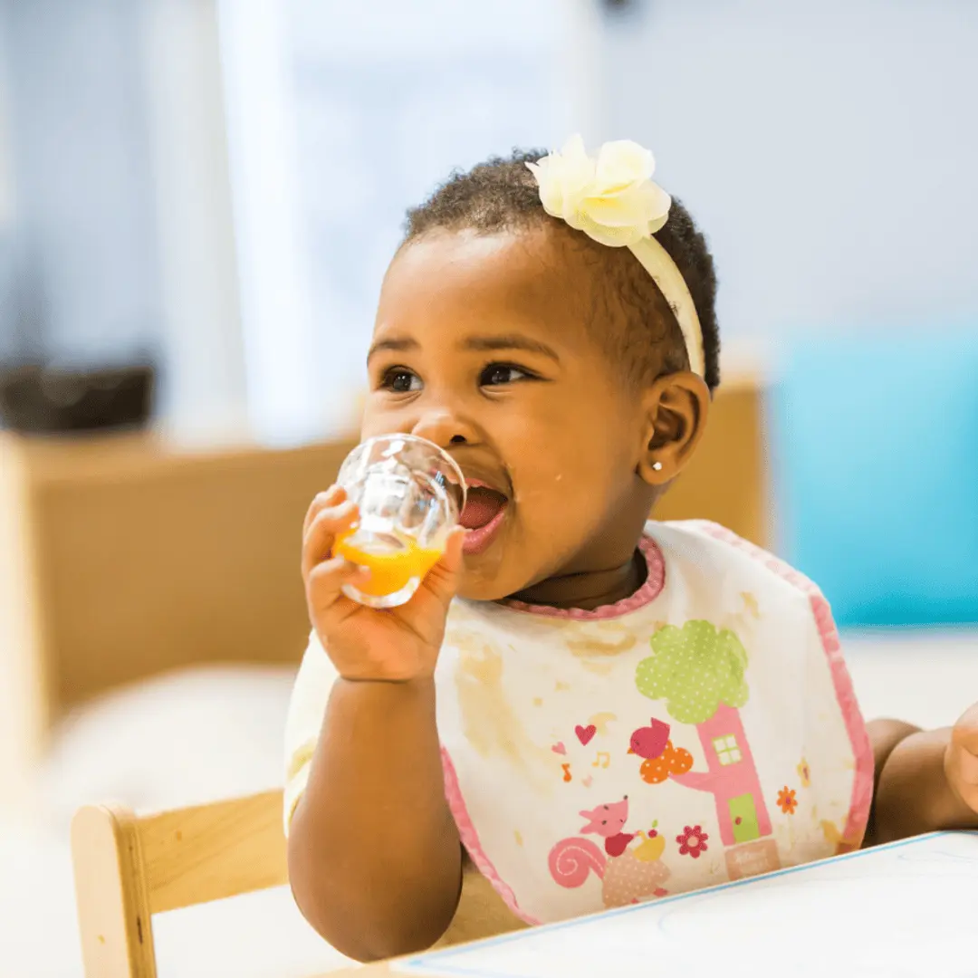 Montessori infant practices independent drinking with a small glass at Guidepost Montessori.